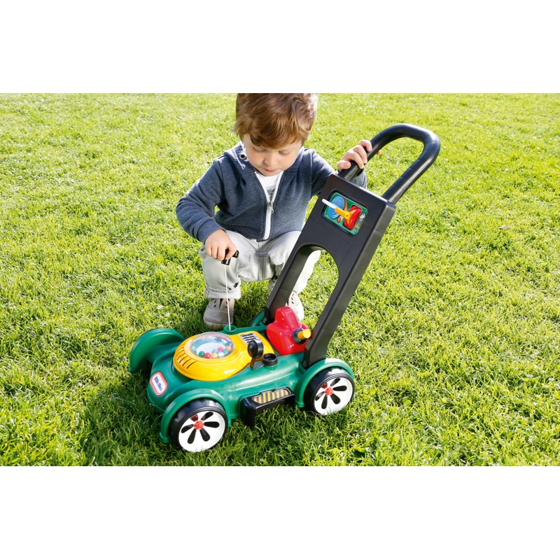 child playing with toy mower in garden